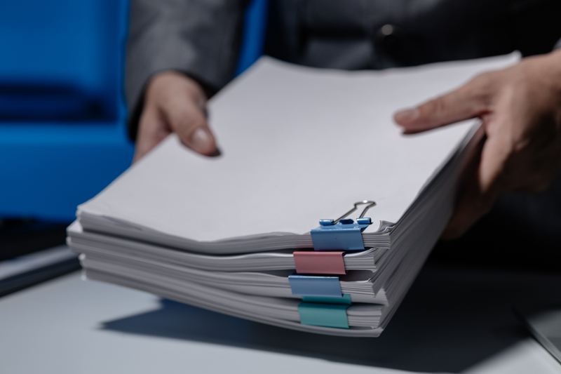 Remise d'une pile de documents à numériser à un prestataire en Valais